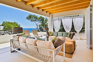 A patio with a couch and chairs with a view of the ocean