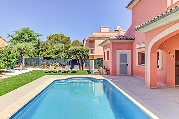 A pink house with a swimming pool in front of it