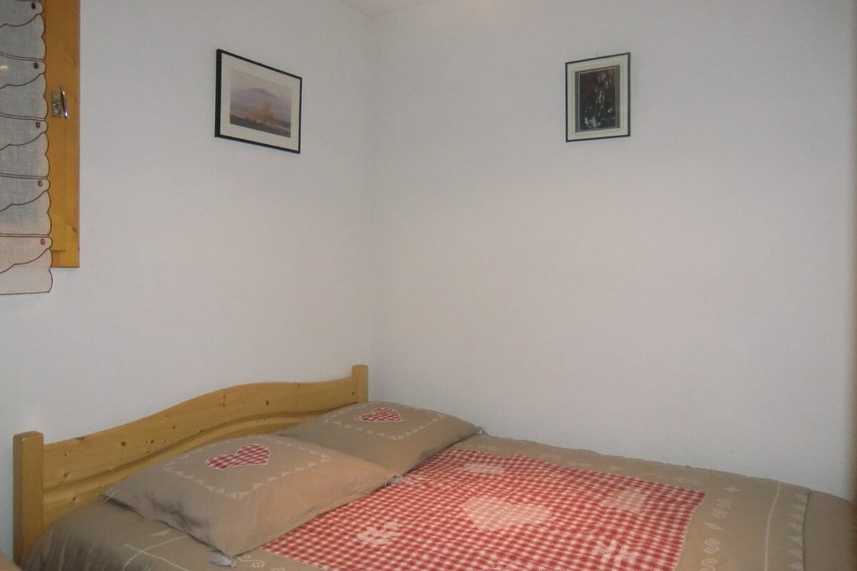 A bedroom with a bed and two pictures on the wall