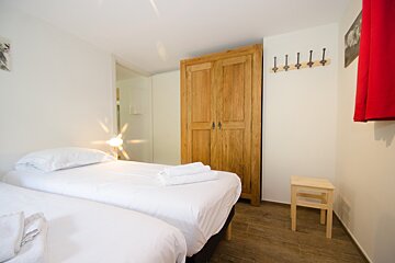 A bedroom with two beds and a wooden wardrobe