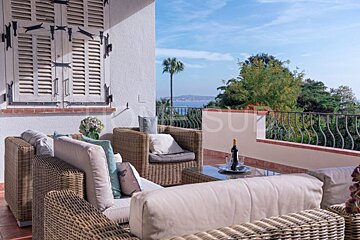 A balcony with wicker furniture and a bottle of wine on a table