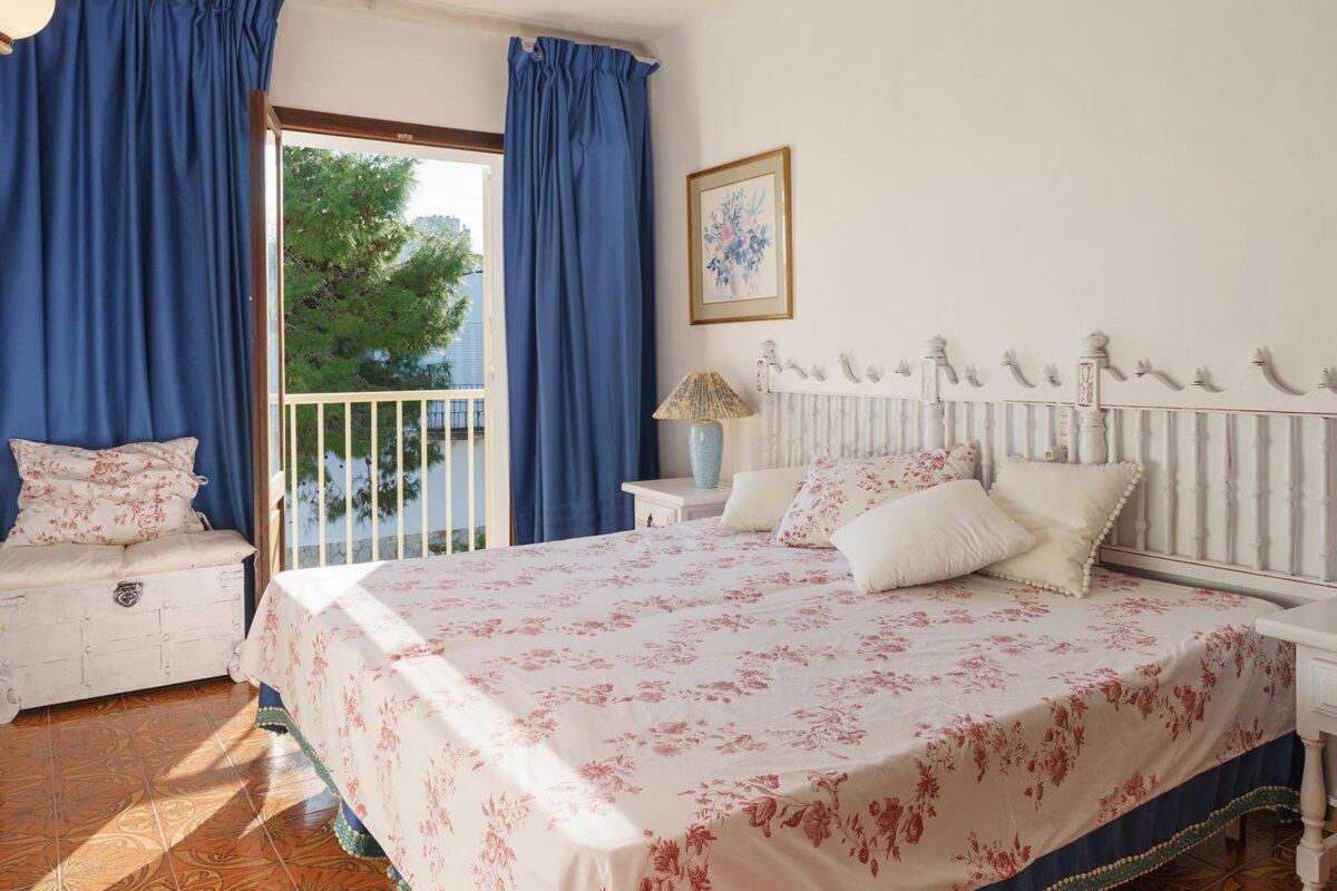 A bedroom with a floral bedspread and blue curtains