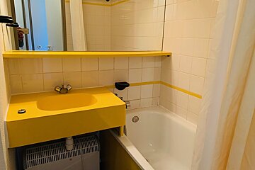 A bathroom with a yellow sink and a white bathtub