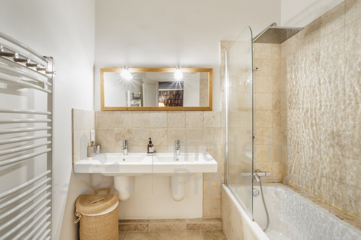 A bathroom with two sinks and a bathtub with a picture of a bookshelf in the background
