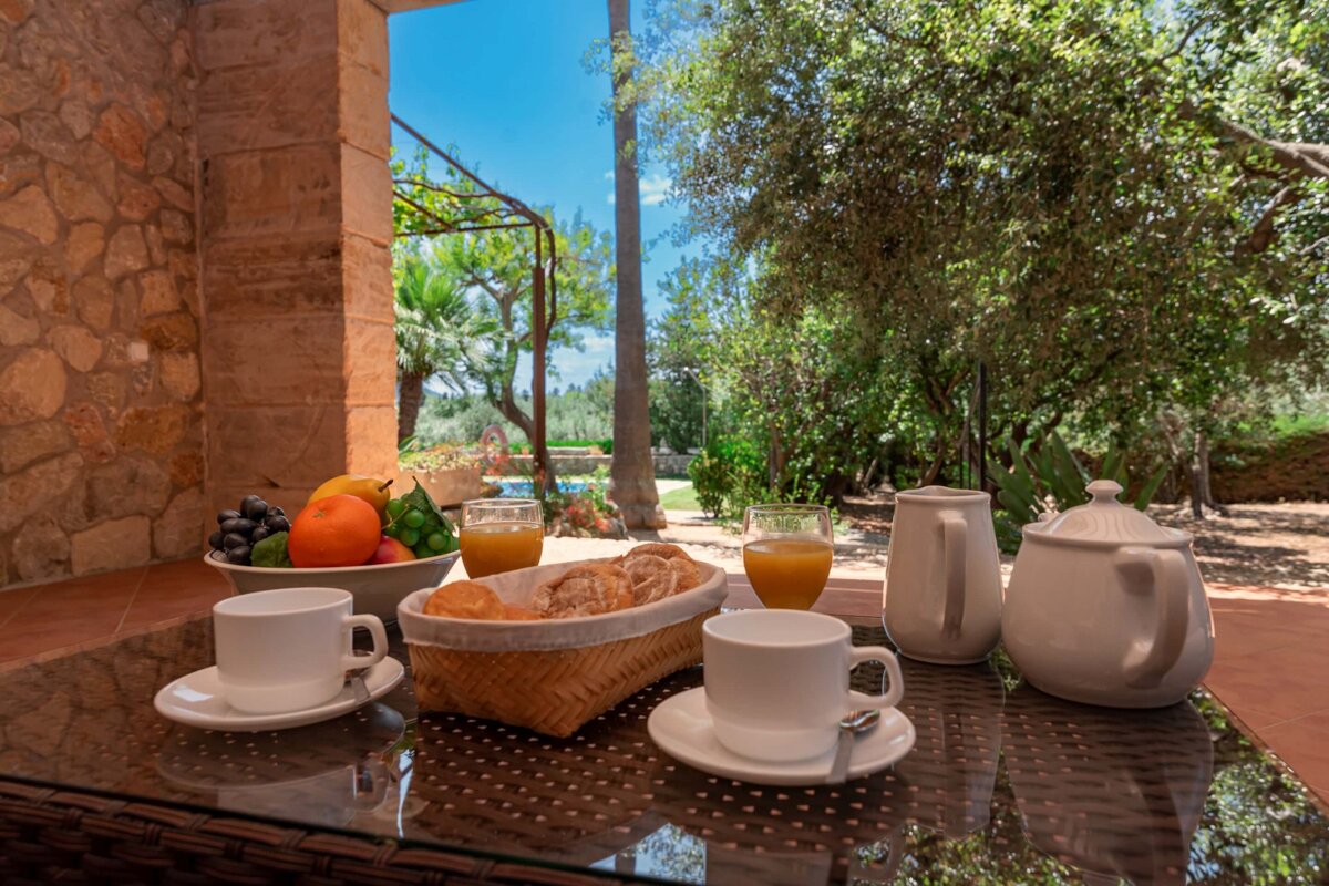 A table with a basket of bread and a bowl of fruit on it
