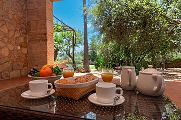 A table with a basket of bread and a bowl of fruit on it