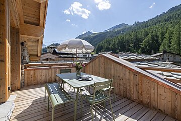 A wooden deck with a table and chairs and an umbrella