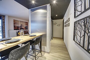 A hallway with a table and chairs and trees on the wall