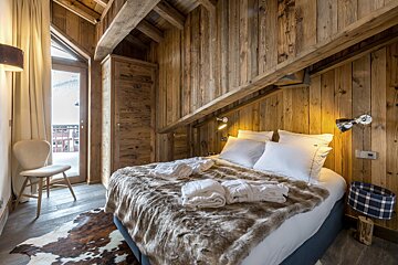 A bedroom with a bed and mirrors on the wall