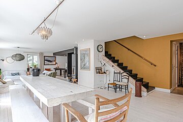 A living room with a table and chairs and a clock on the wall
