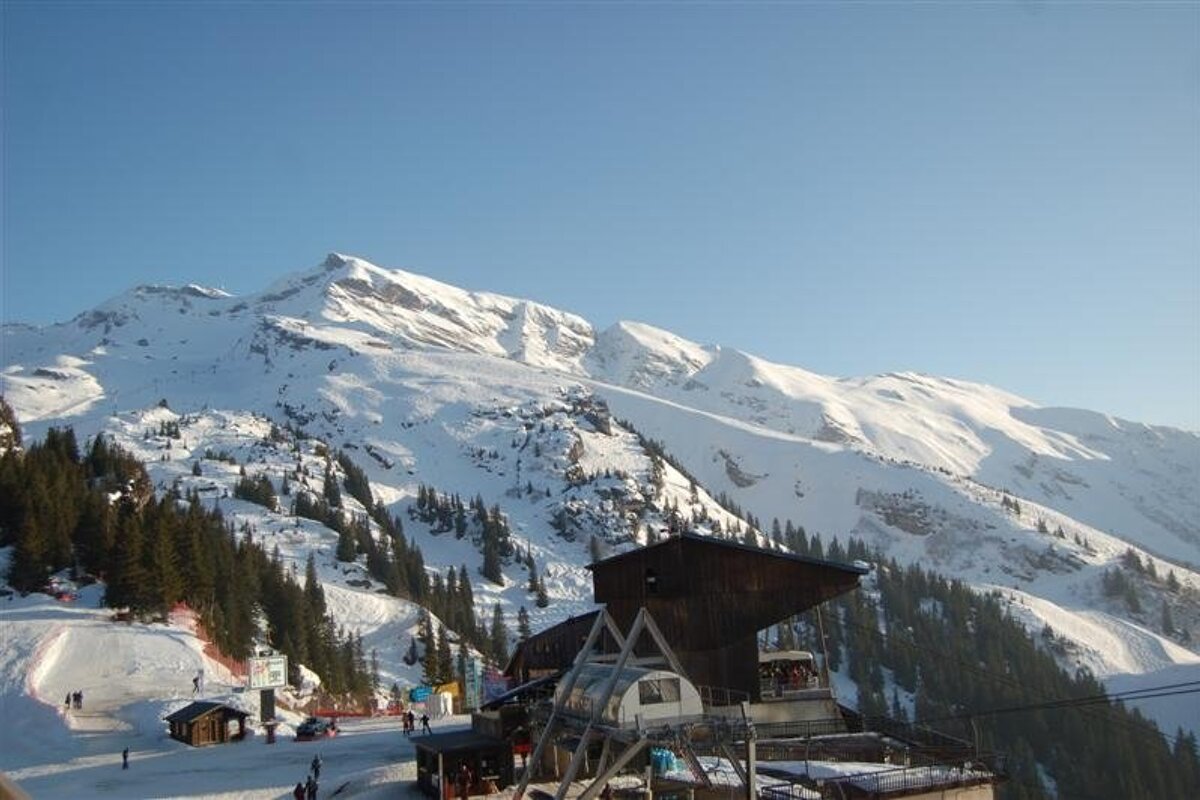 A ski lift going up a hill with mountains in the background