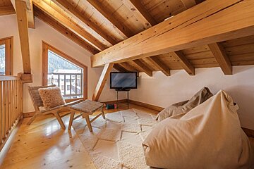 A corner of a room with a bean bag chair and a flat screen tv