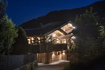 A large wooden house is lit up at night