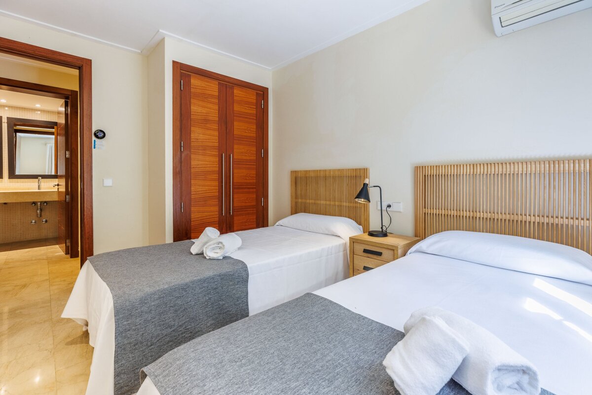 A bedroom with two beds and a lamp on the nightstand