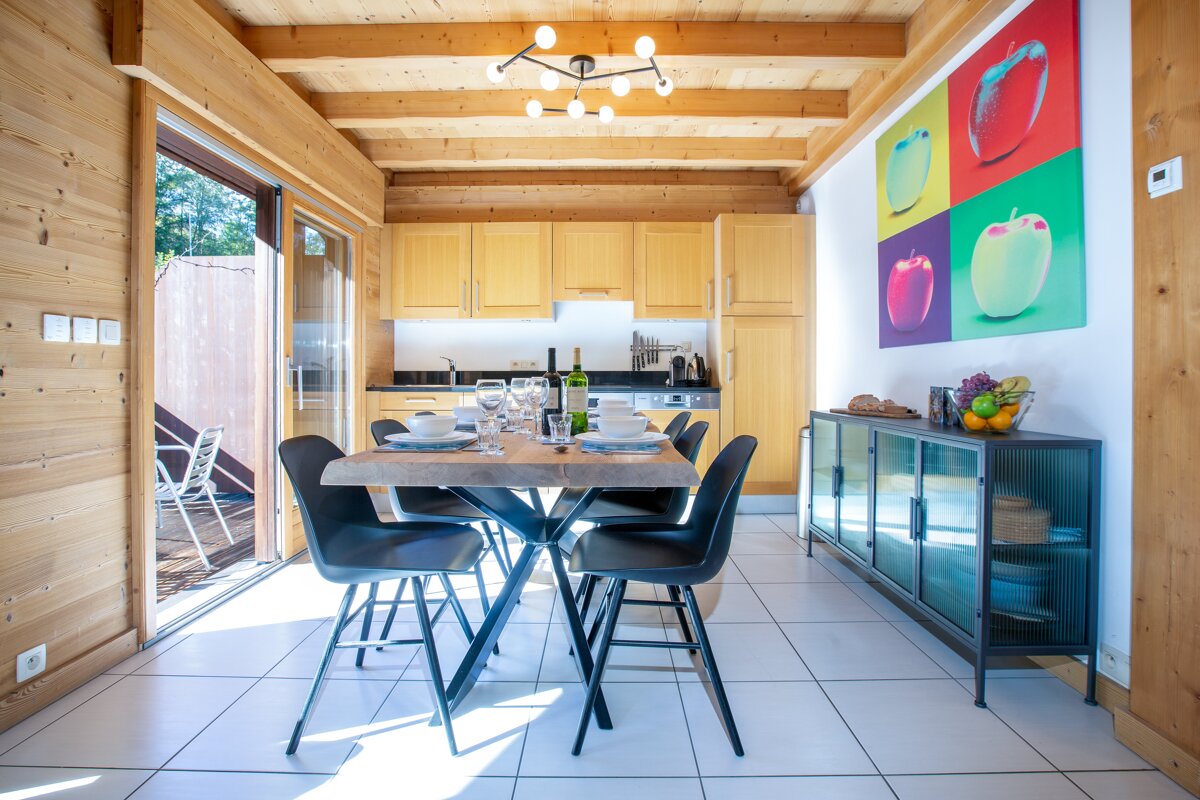A dining room with a table and chairs and a painting of apples on the wall
