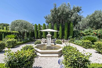 A garden with a fountain and a white umbrella