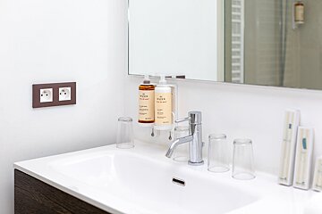 A bathroom sink with a bottle of nuxe on it