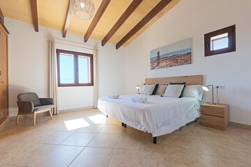 A bedroom with a large bed and a picture on the wall