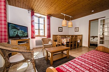 A living room with a table and chairs and a flat screen tv