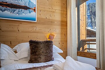 A bedroom with a picture of a mountain on the wall above the bed