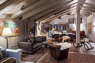 A living room with a couch and chairs and a painting on the wall