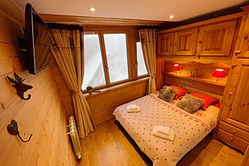 A bedroom with a bed and a television on the wall