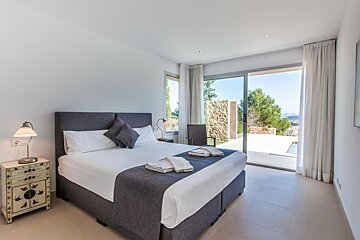 A bedroom with a large bed and a sliding glass door