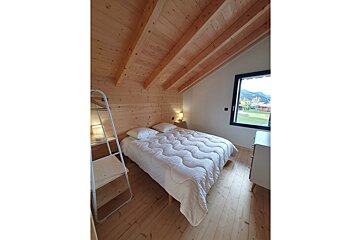 A bedroom with a bed and a window with mountains in the background