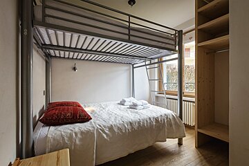 A bunk bed with white sheets and a red pillow