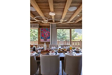 A dining room with a table and chairs and a painting on the wall