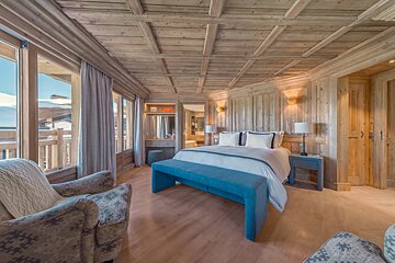 A bedroom with a large bed and a blue bench