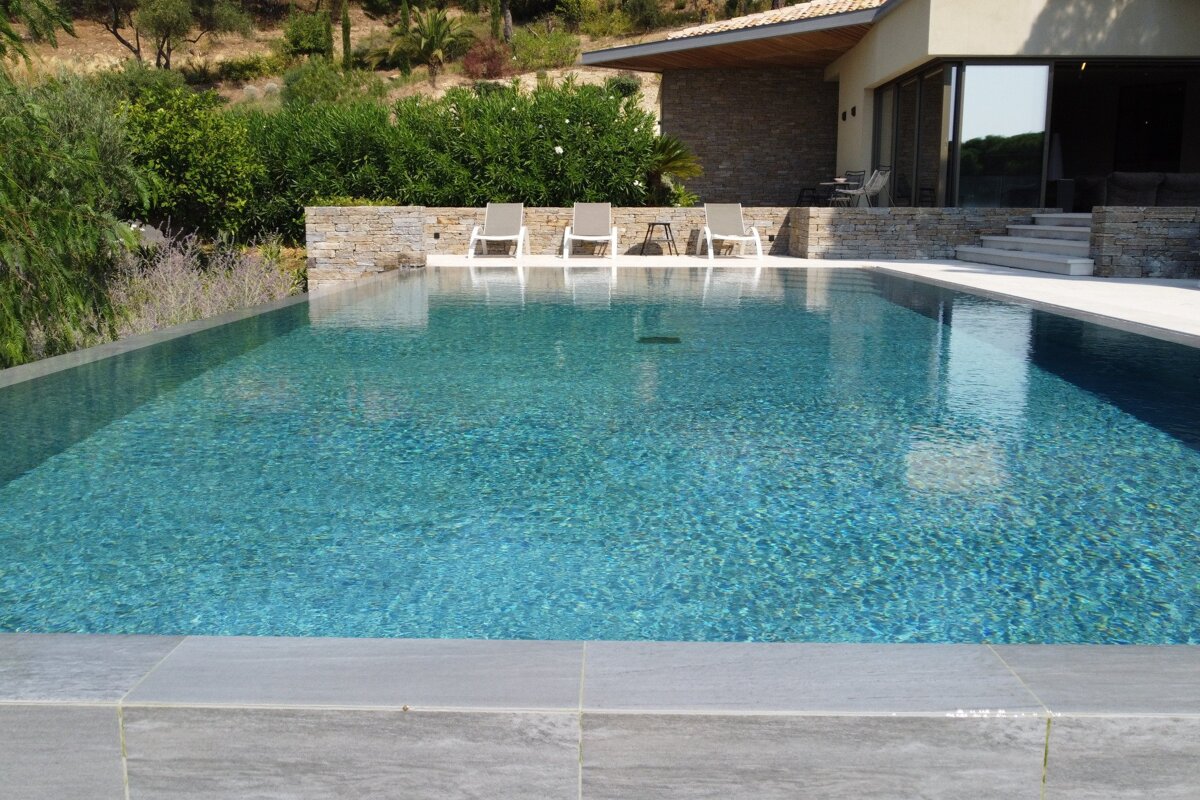 A large swimming pool with a house in the background