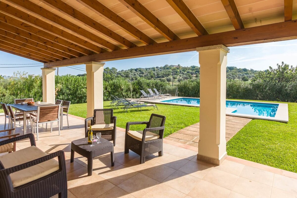 A patio with chairs and a table with a bottle of wine on it