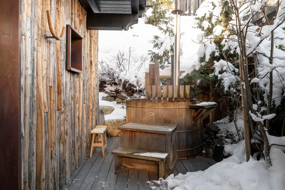A wooden tub with stairs leading up to it is surrounded by snow