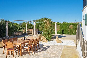 A patio with a table and chairs and a bottle of wine