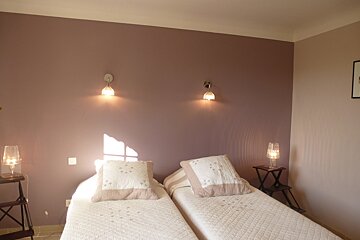 A bedroom with two beds and two lamps on the wall