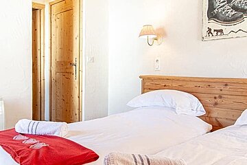 A bedroom with two beds and a painting on the wall