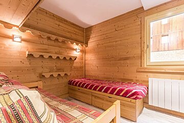 A wooden room with two beds and a window