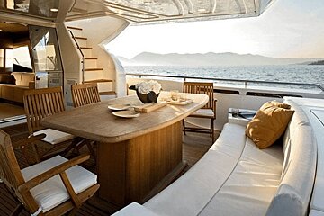 A table and chairs on a boat with mountains in the background