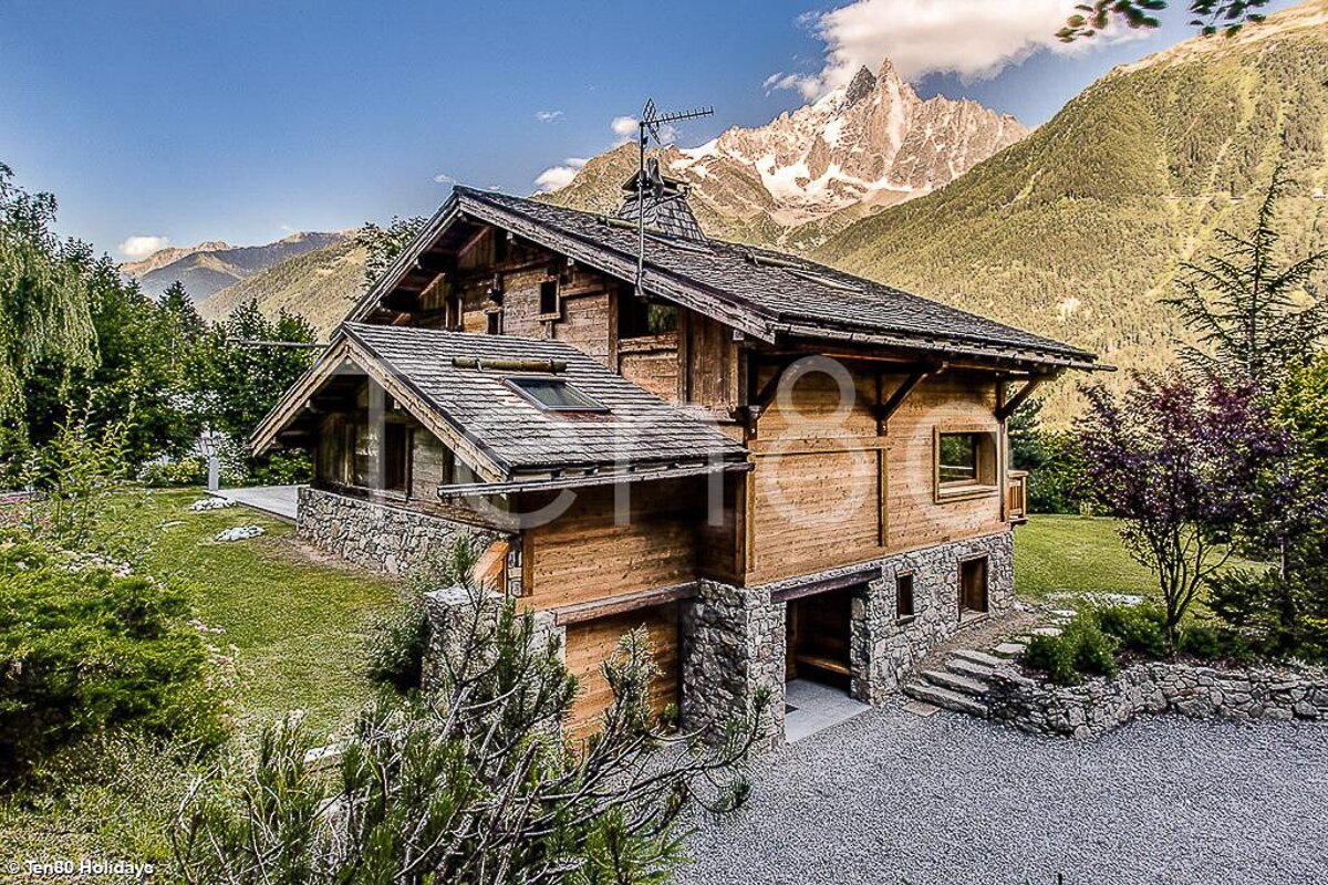A photo of a wooden house with a mountain in the background