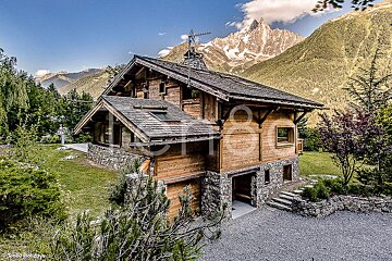 A photo of a wooden house with a mountain in the background