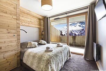 A bedroom with a sliding glass door leading to a balcony