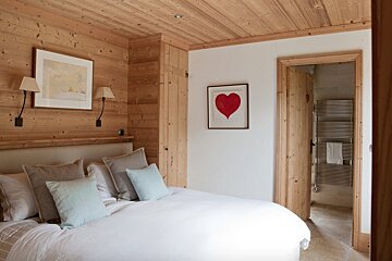A bedroom with a bed and a picture of a heart on the wall