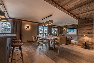 A dining room with a table and chairs and a flat screen tv