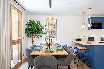 A dining room table with a bottle of wine on it