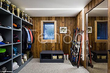 A room with a lot of skis and trophies on the shelves