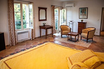 A bedroom with a yellow bed and two chairs