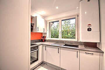 A kitchen with white cabinets and a white water heater