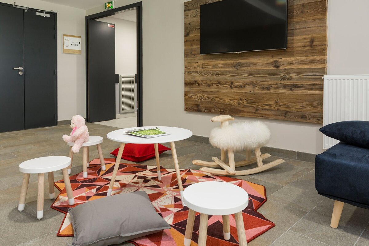 A rocking horse sits on a rug in front of a television