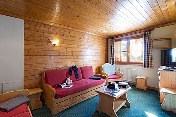 A living room with wood paneling and a red couch